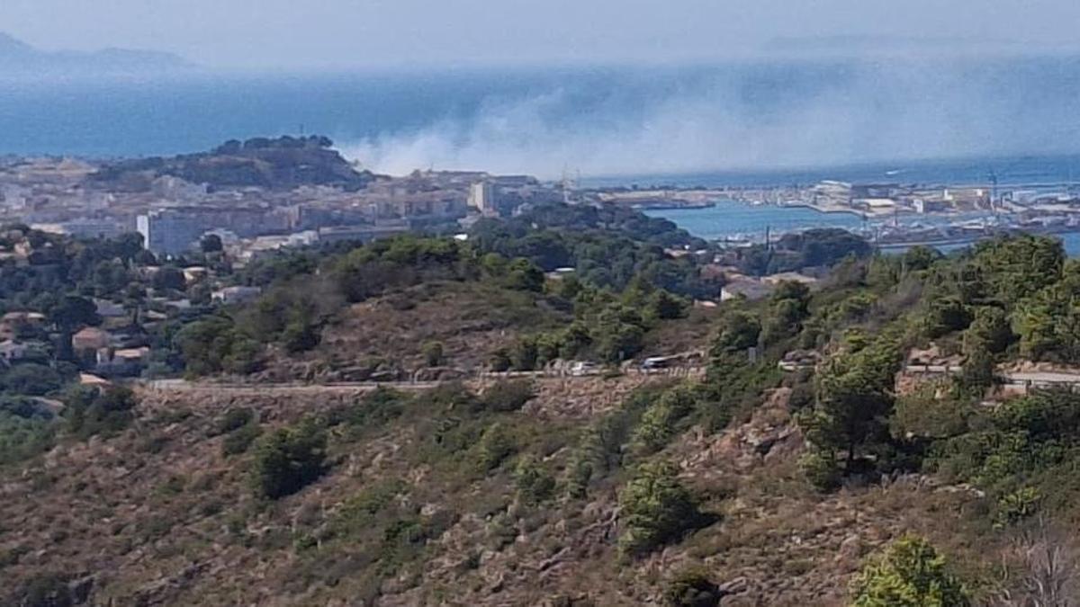La imagen que se ve desde les Planes: el humo sale de detrás del castillo y se mete en el mar