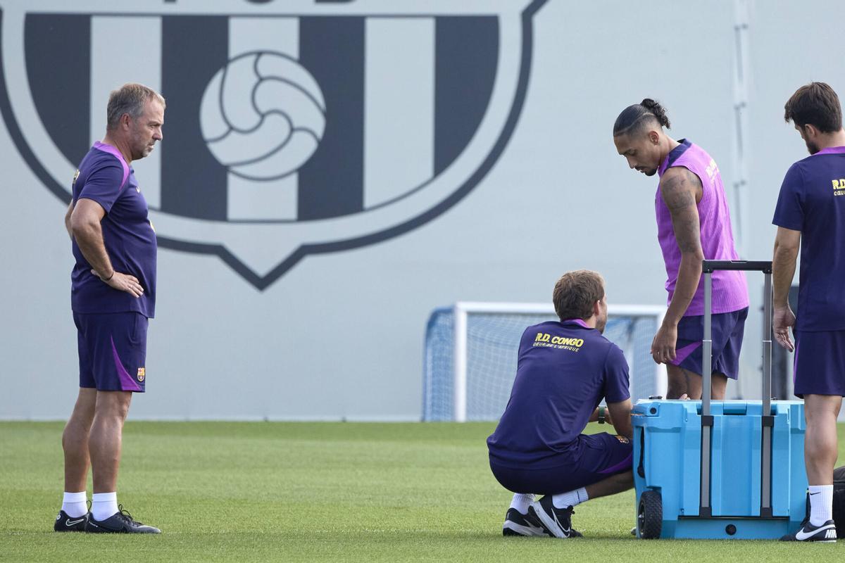 Hansi Flick observa cómo atienden a Raphinha en el inicio del entrenamiento de este sábado.