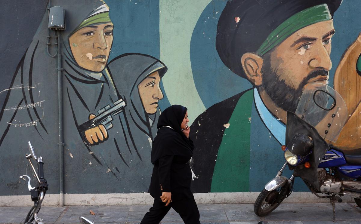 Una mujer camina frente a un mural con dibujos de soldados revolucionarios, este miércoles en Teherán.