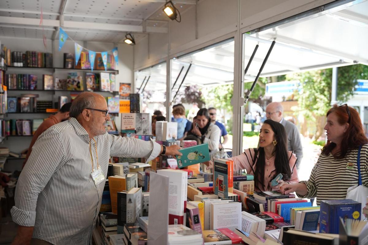 José Luis Marín, propietario de Librería Colón, atiende a una clienta en la Feria del Libro de Badajoz.