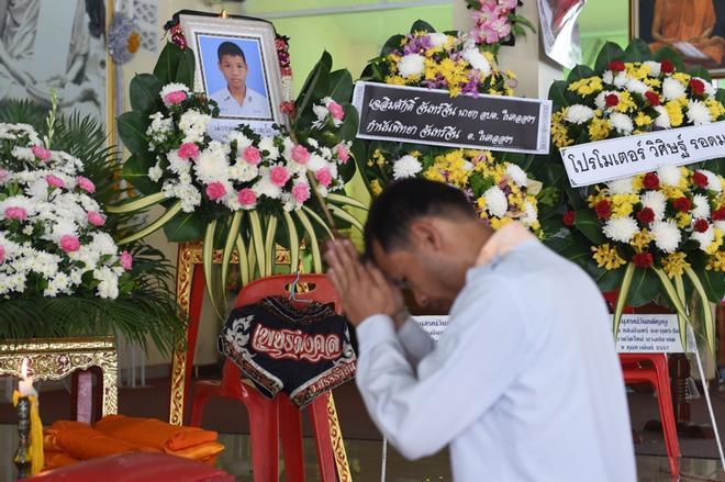 Un doliente reza frente a un retrato del boxeador de Muay Thai de 13 años de edad, Anucha Tasako, junto a su ataúd durante un funeral en un templo budista en la provincia de Samut Prakan.