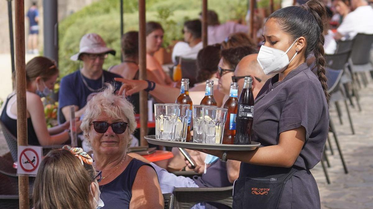 Una cambrera serveix beguda a uns turistes en un bar