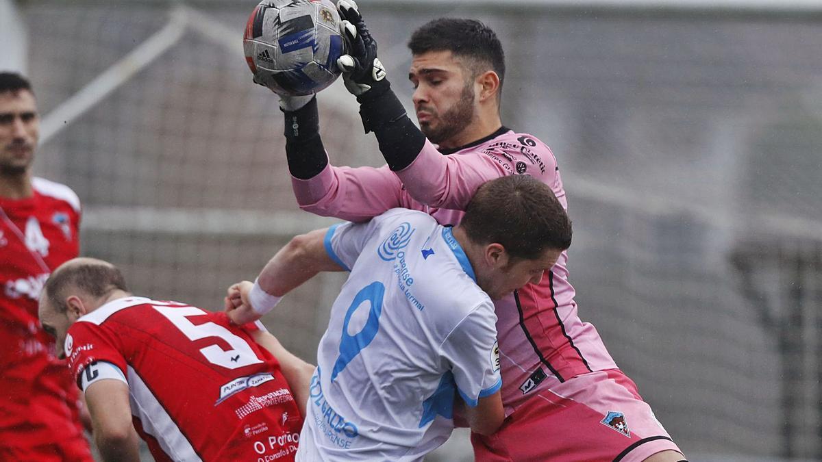 El guardameta local Diego atrapa un balón que también buscaba Hugo García, ayer, en el campo de O Carballo de Atios. |  // RICARDO GROBAS