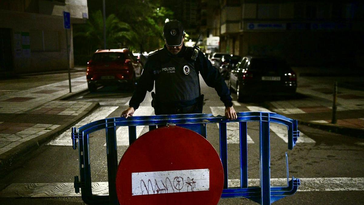 Un policía local coloca la valla de acceso prohibido en La Madrila.