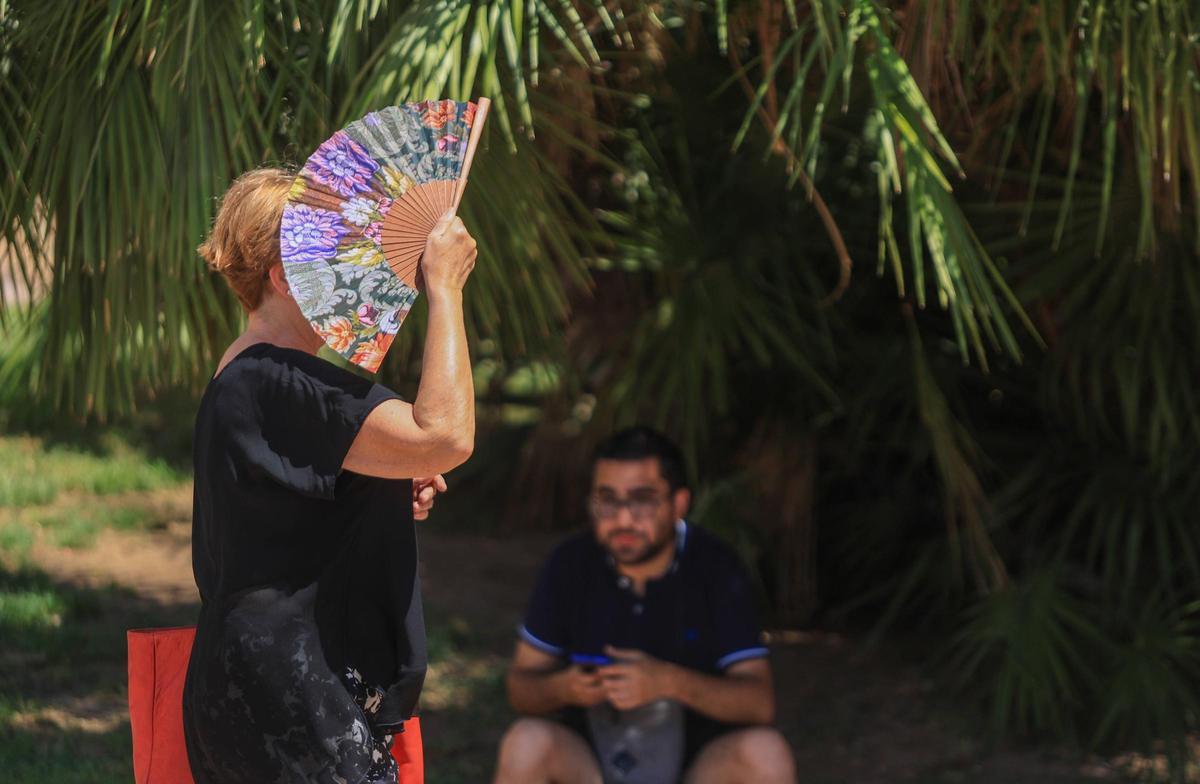 Una mujer se protege del sol con un abanico en el centro de València, esta mañana.