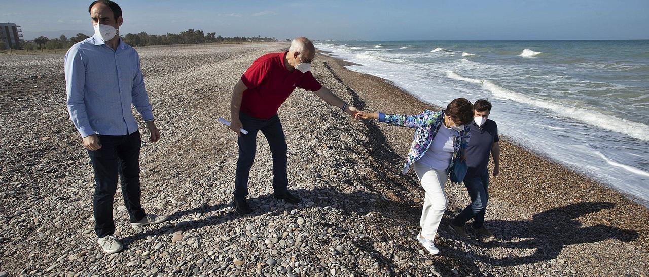 El edil Javier Raro junto a representantes de la asociación de vecinos, en una zona de la playa con desniveles hasta llegar al mar. | DANIEL TORTAJADA