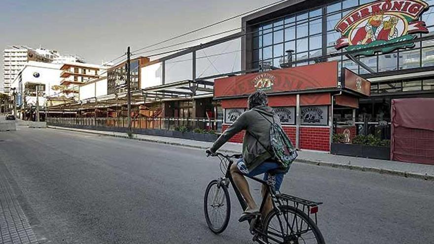 Un ciclista pasa por delante del popular Bierkönig, cerrado desde el inicio del estado de alarma, en una desértica calle del Jamón de la Platja de Palma.