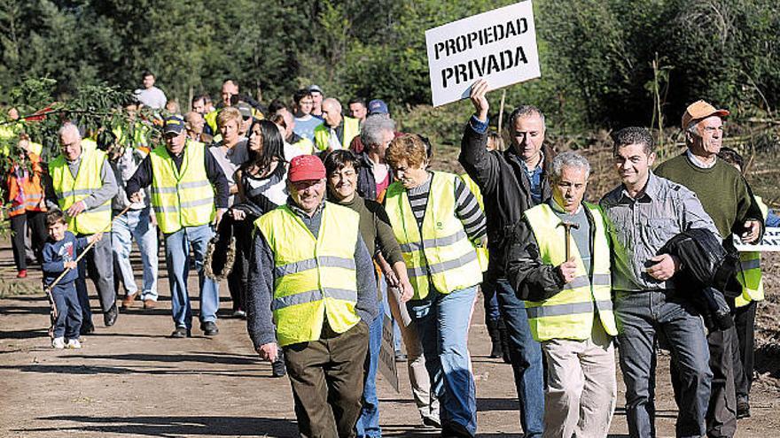 Un vecino de Salcedo cuelga un cartel en una de las parcelas del monte comunal afectado.  // Rafa Vázquez