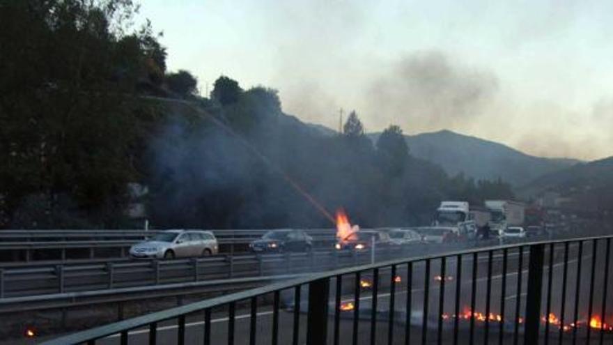 El IMPACTO. Momento en el que uno de los voladores estalla contra uno los vehículos detenidos por la barricada. A la derecha, el conductor del coche, Sergio Sagredo, muestra sus heridas. | álvaro fuentes / vivas