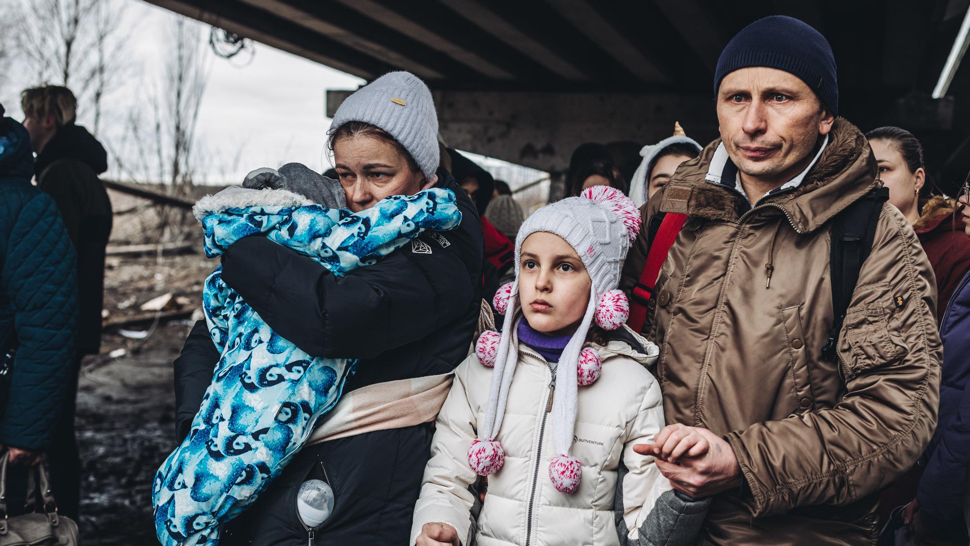 Una familia de refugiados ucranianos con niños esperan para cruzar el río de Irpin.