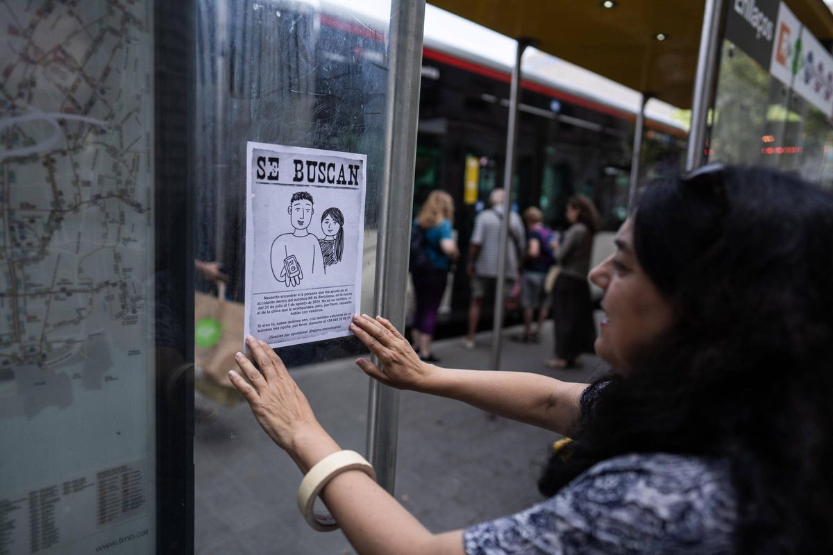 Arantxa Morán cuelga un cartel en una parada de bus en el centro de Barcelona.