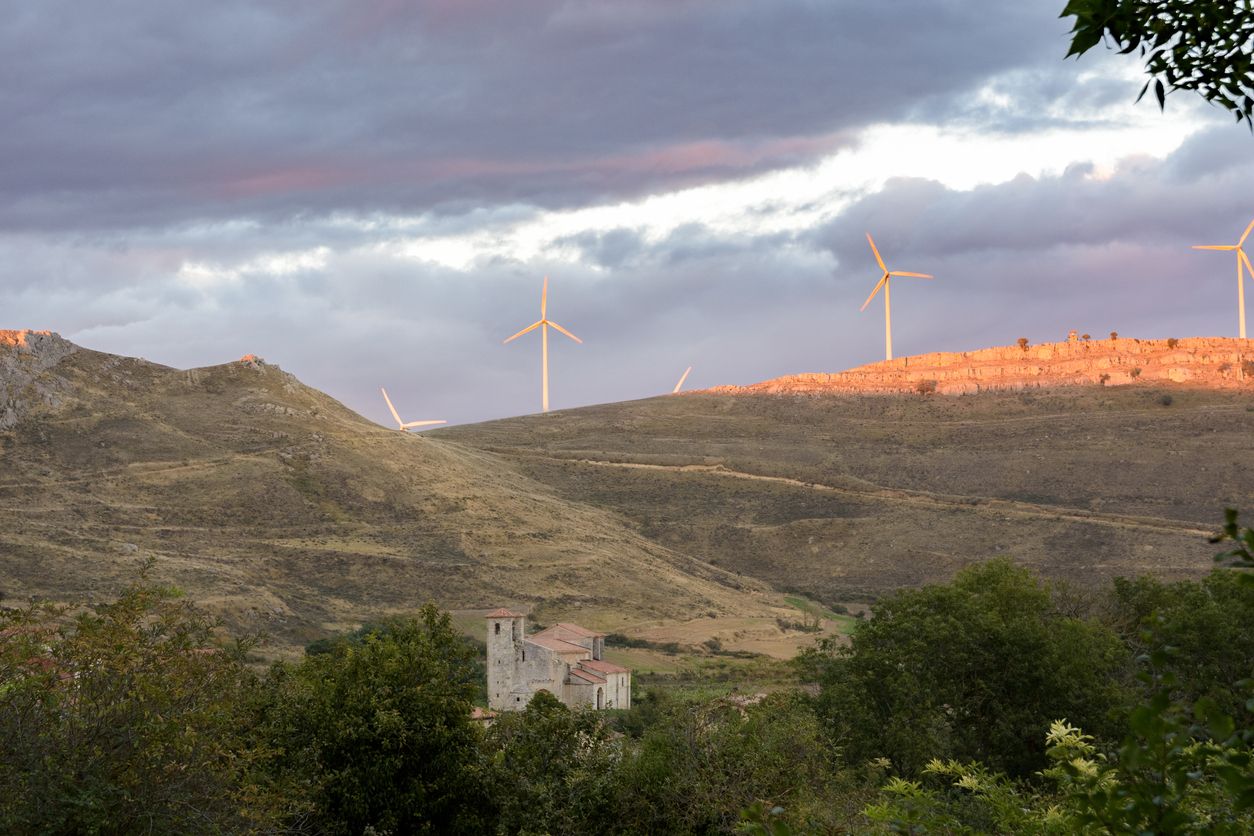 Vista de la Iglesia del Monasterio de Rodilla con montañas y turbinas al fondo.