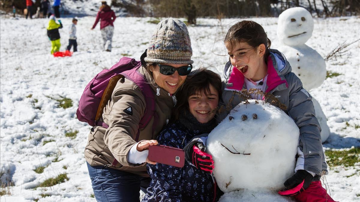 Una mujer realiza un ’selfie’ a cuatro tras dar por terminada la labor de levantar un muñeco de nieve, este, sin zanahoria.