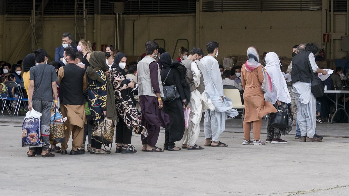 Varios refugiados tras la llegada de un avión con 260 personas procedentes de Afganistán, en la base aérea de Torrejón de Ardoz.