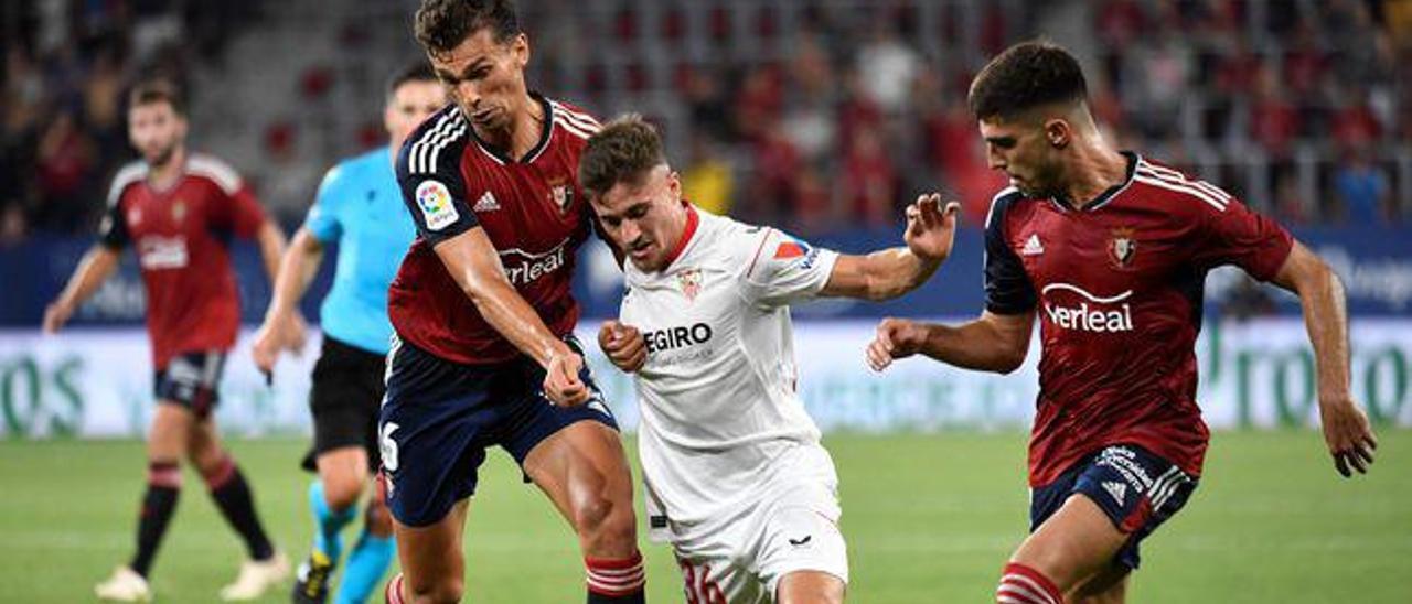 Iván Romero, entre dos rivales en el partido liguero entre Sevilla y Osasuna. | | E.D.