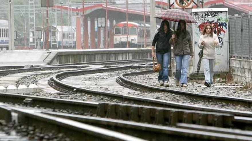 Tres jóvenes caminan por las vías en el tramo que el Adif vallará y que desaparecerá en 2010