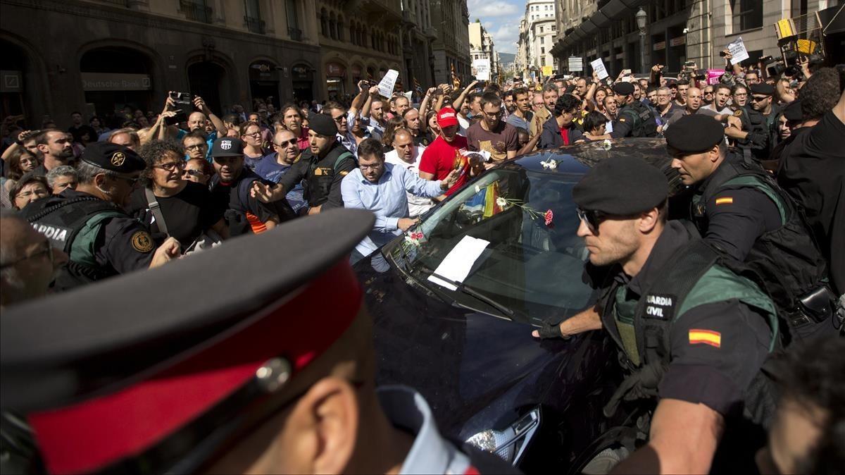 Diversos manifestantes tratan de impedir la salida del vehículo en la que la Guardia Civil se lleva uno de los detenidos en la Conselleria d’Afers Exteriors.