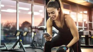Una mujer con su móvil en un gimnasio.