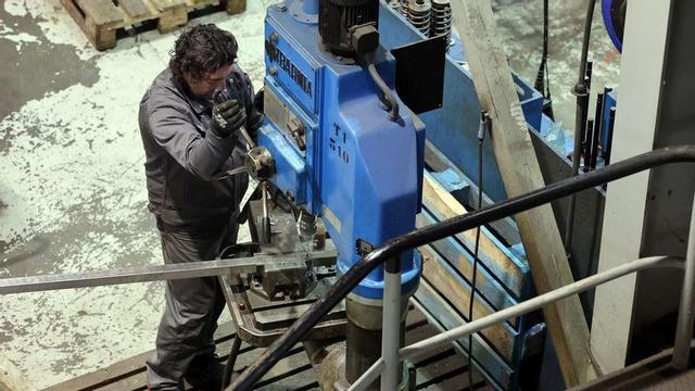 Un trabajador manipula una pieza de metal.