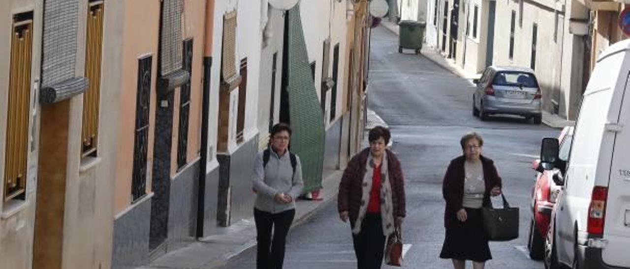 Dos vecinos, el jueves, toman el sol en un banco a la entrada del pueblo.