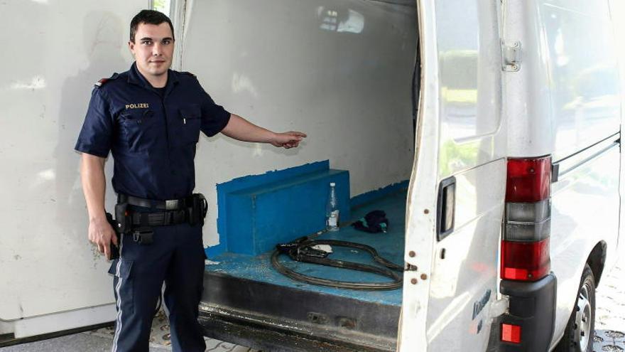 Un policía muestra la furgoneta que trasportaba a los refugiados.