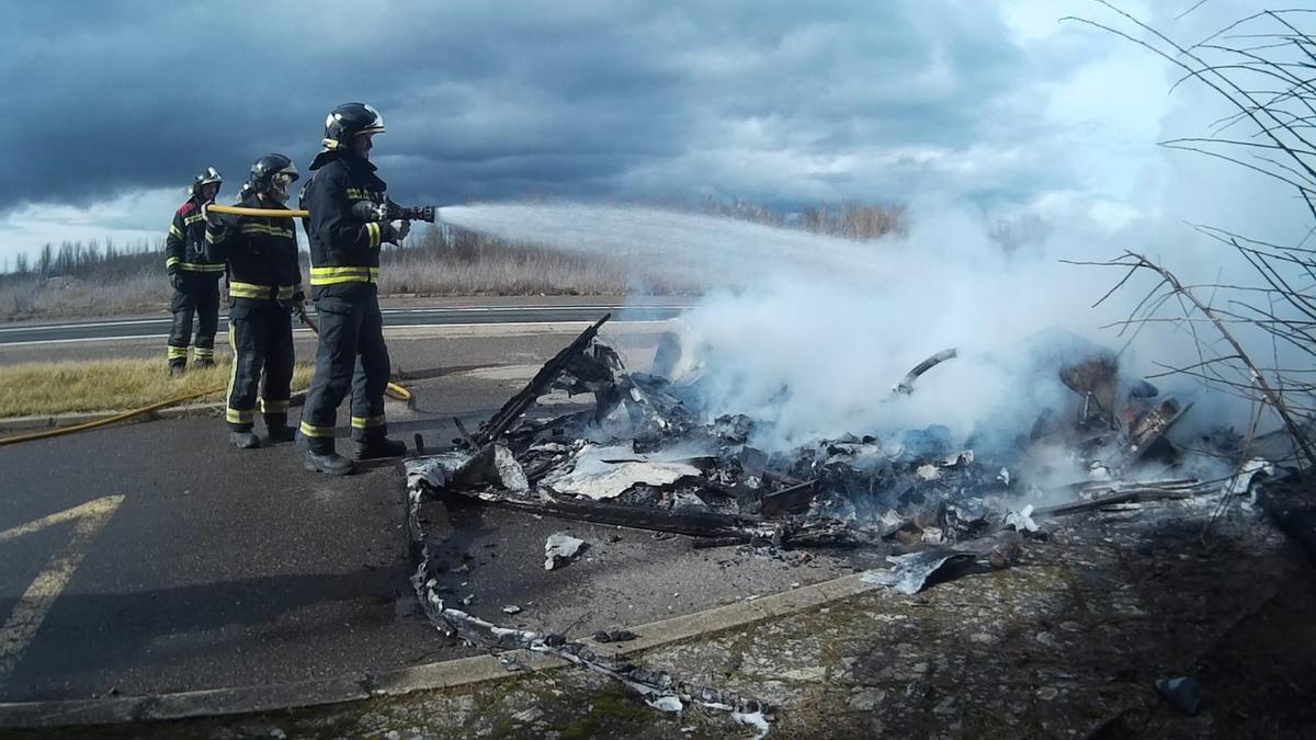 Un equipo de Bomberos apaga la caravana incendiada.