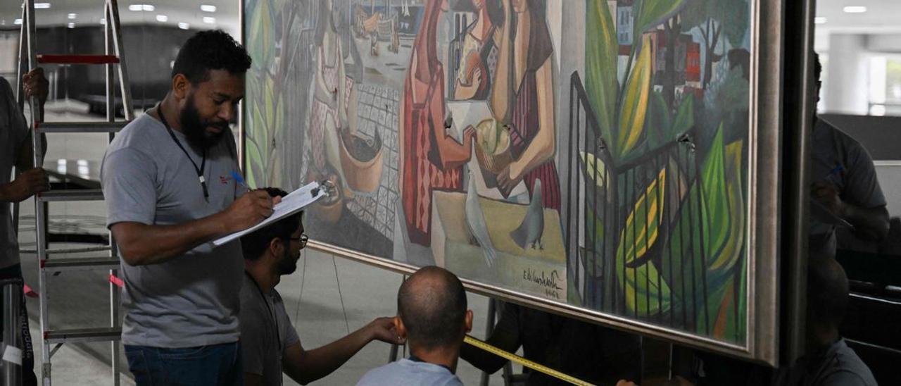 Trabajadores evalúan los daños infligidos en el cuadro ’Mulatas’ del pintor brasileño Emiliano di Cavalcanti por parte de los bolsonaristas que asaltaron el Palacio de Planalto.