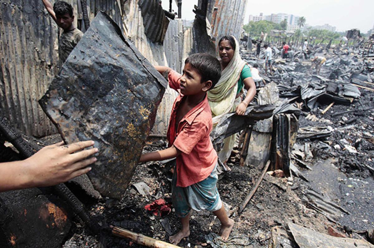 Un nen i la seva família intenten recuperar algunes pertinences seves després d’un incendi que ha cremat més de 150 vivendes i ha deixat almenys 10 persones ferides, a Dacca (Bangla Desh).
