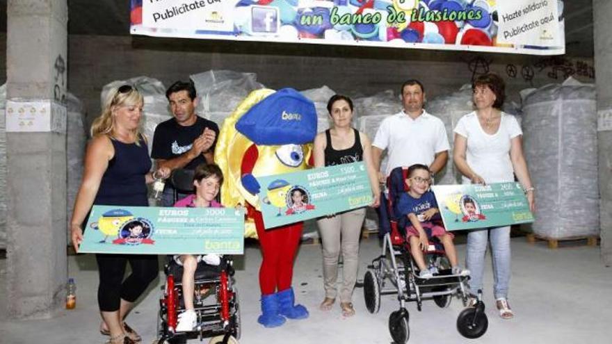 Los niños Carlos Cambra y Adrián Chao, con sus familias y el muñeco del banco de tapones.  // José Lores