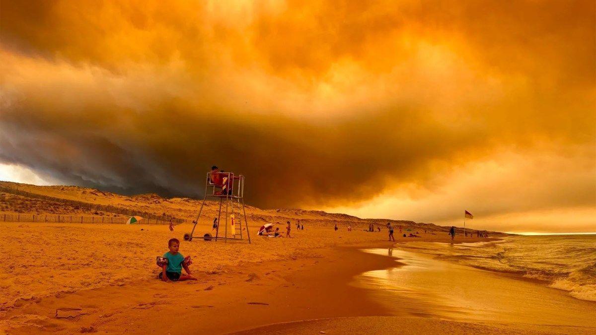 Imagen de la playa de Lacanau en Francia el 24 de julio, con una densa columna de humo de un incendio forestal cerca de Burdeos.