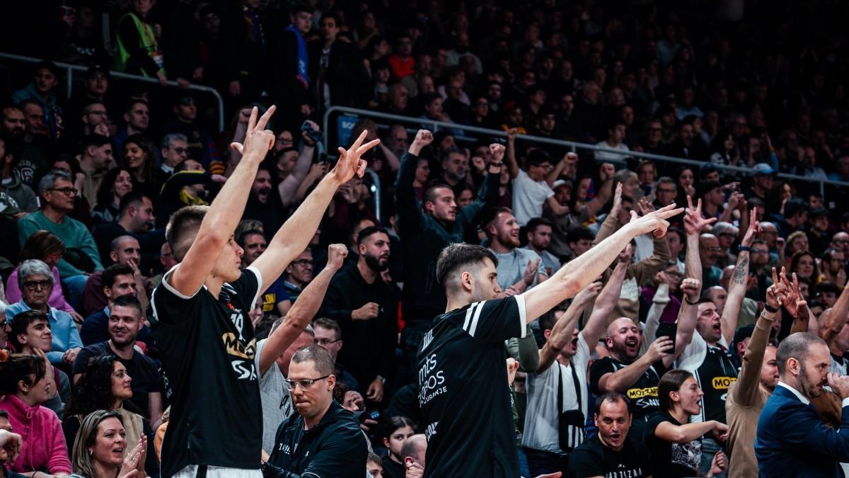 El banquillo de Partizán celebra una canasta del equipo ante el apoyo de su afición, esparcida por el Palau
