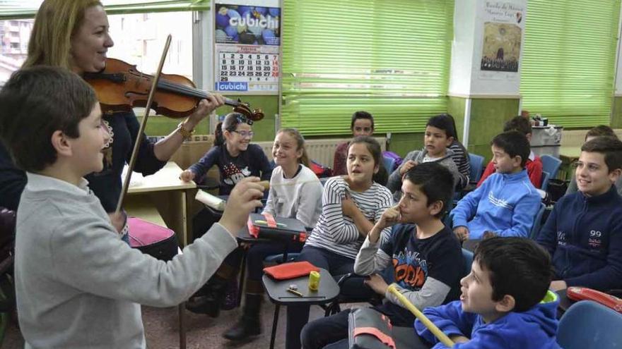 La profesora de música con el violín, mientras un alumno (izquierda) hace de director de orquesta.