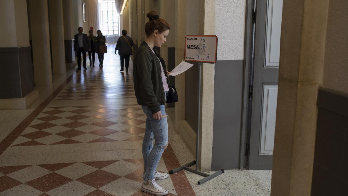 PASILLO DE UN COLEGIO ELECTORAL, UNA MUJER CONSULTA EL CENSO