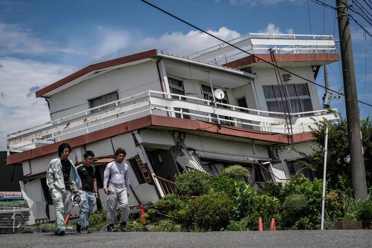 Los trabajadores pasan junto a una casa dañada y se derrumbaron parcialmente en la prefectura de Yatsushiro, Kumamoto, el 29 de julio de 2026, después de que un terremoto sacudió el suroeste de Japón el día anterior. (Foto de Yuichi YAMAZAKI / AFP)