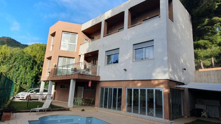 Vista de la parte exterior frontal de la vivienda, con la piscina como protagonista.
