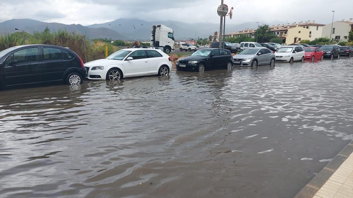 Imagen de una hilera de coches estacionados en una calle anegada de Benicàssim.