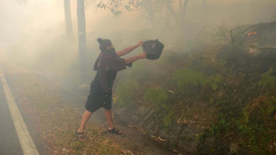 Aunque los mayores momentos de tensión y miedo se vivieron de madrugada, por la mañana los vecinos seguían trabajando en la extinción del fuego con los medios que tenían a su alcance, como se puede ver a esta mujer de origen francés residente en O Lago (Cea).