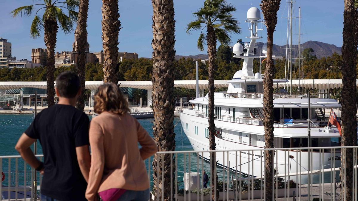 Una pareja observa un yate atracado en el puerto de Málaga.