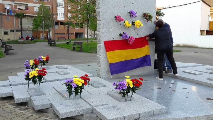 Dos personas colocan una bandera republicana en el monumento &quot;Memoria herida&quot;, en Grado.