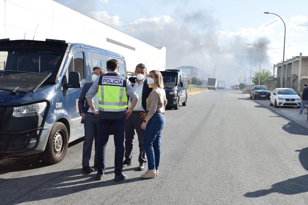 Representantes institucionales con el incendio de la nave de Plainsur de fondo