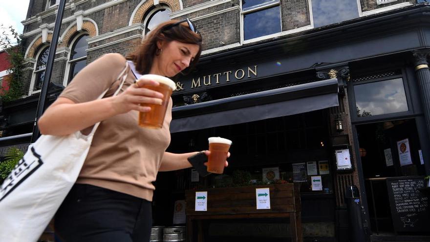 Una clienta lleva dos cafés en un barrio de Londres.