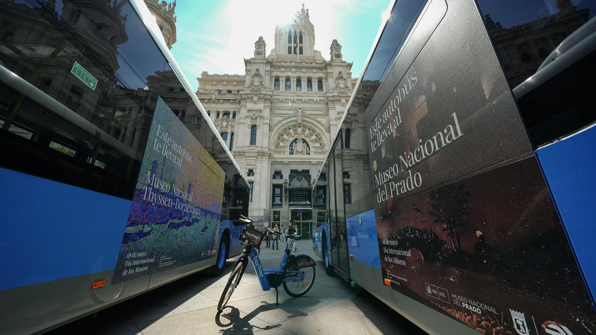Dos autobuses y una bici municipal adornados con la imagen de la campaña.