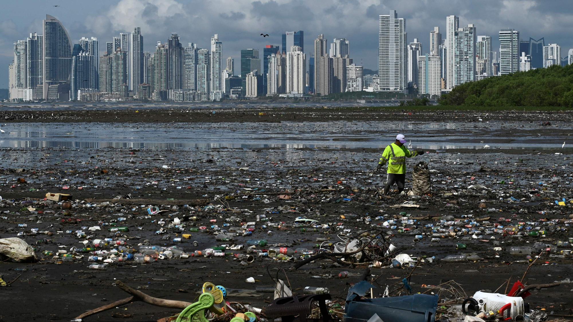 A man collects garbage, including plastic waste, at the beach of Costa del Este, in Panama City, on April 19, 2021. - Every two weeks, Marine Biology students descend about five meters in the sea to take care of a coral nursery of the staghorn species (Acropora cervicornis) in Portobelo, Panama, with which they aim to restore reefs damaged by climate change and pollution, as part of the Reef2Reef project. (Photo by Luis ACOSTA / AFP)