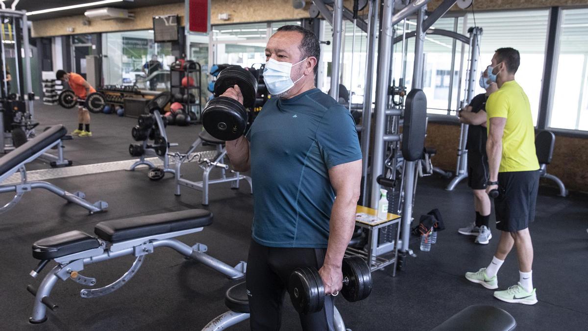 Un ciudadano realiza ejercicio en un gimnasio armado de mascarilla