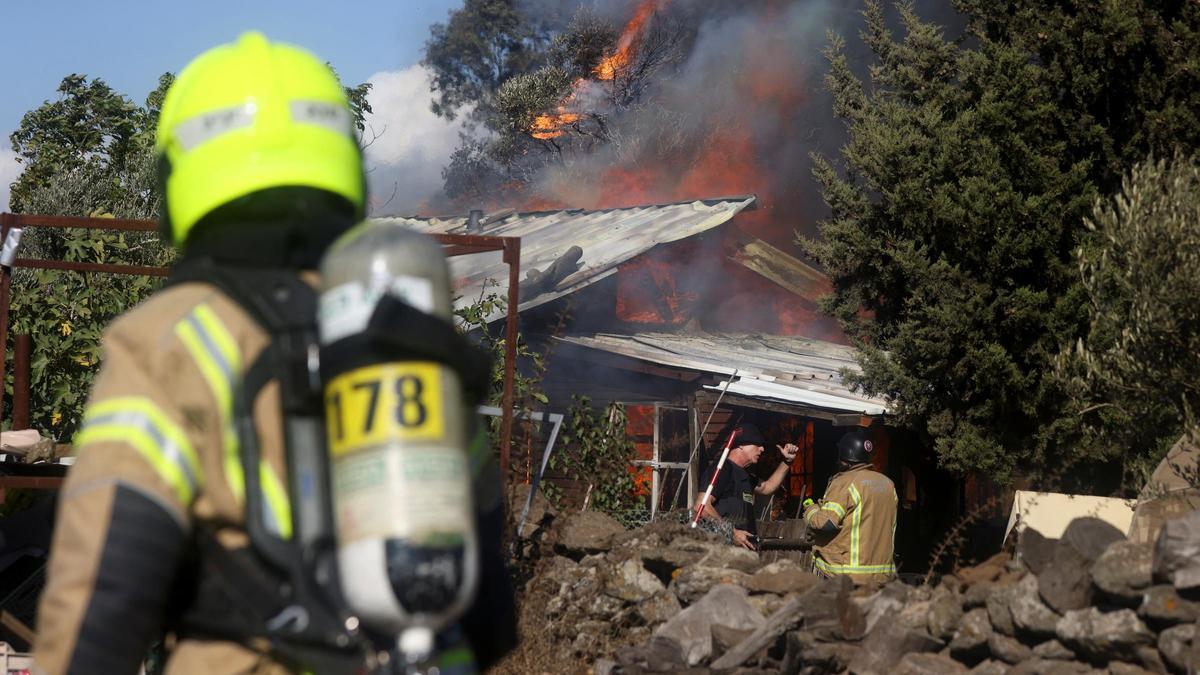 Los equipos de rescate trabajan para extinguir las llamas en una casa tras un ataque con cohetes desde el Líbano, en el norte de Israel.