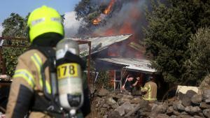 Los equipos de rescate trabajan para extinguir las llamas en una casa tras un ataque con cohetes desde el Líbano, en el norte de Israel.