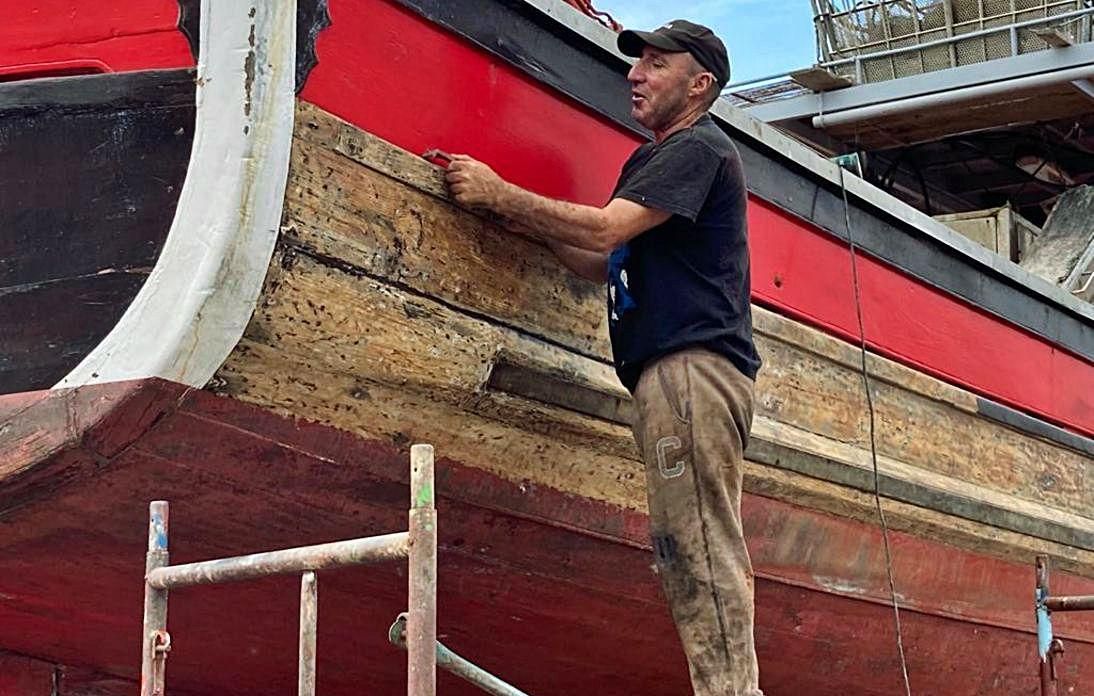 Un vecino de O Grove rasca el casco de una nave antes de pintarla, ayer.