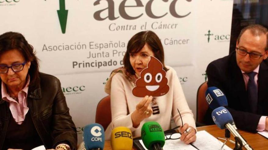 Margarita Fuente, sentada entre Margarita Collado y Antonio Molejón, muestra la imagen de la campaña de detección precoz del cáncer de colon.