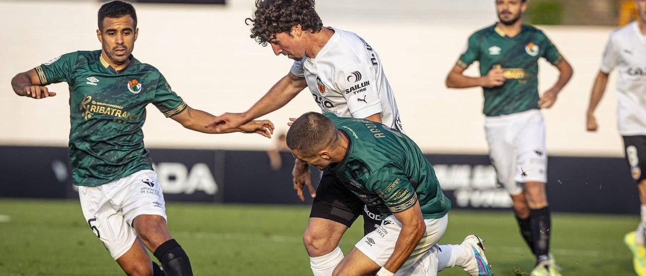 Telles y Luis Aguado, autor del gol del Cacereño, intenta frenar a un jugador del Valencia Mestalla.