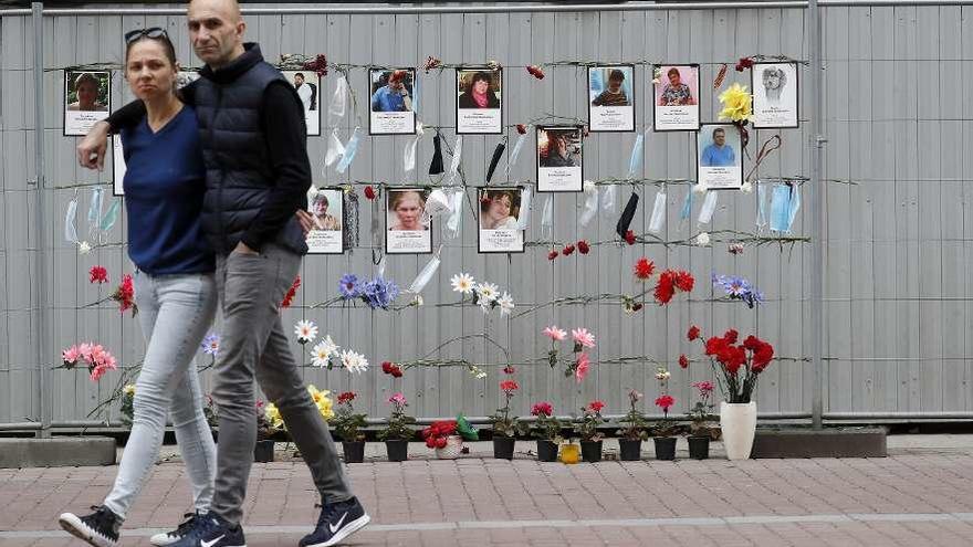 Una pareja pasa por delante de un espacio de homenaje a sanitarios fallecidos en Moscú. // Efe